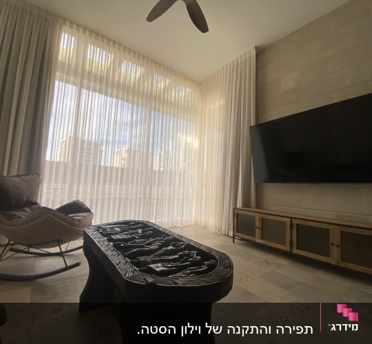 וילונות לבנים בחדר עם כורסה ושולחן מעוצב